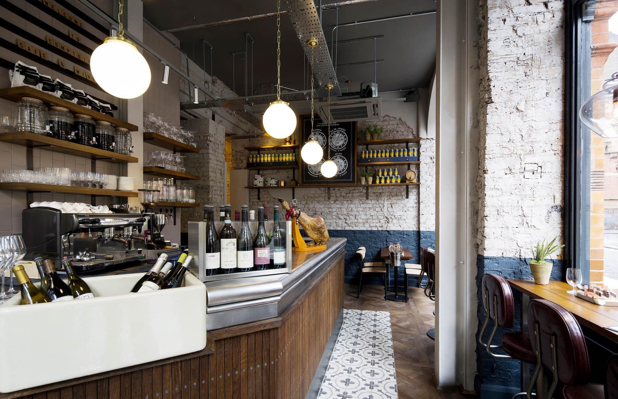 Looking along the bar at Comptoir, wine bottles in front and globe pendants above