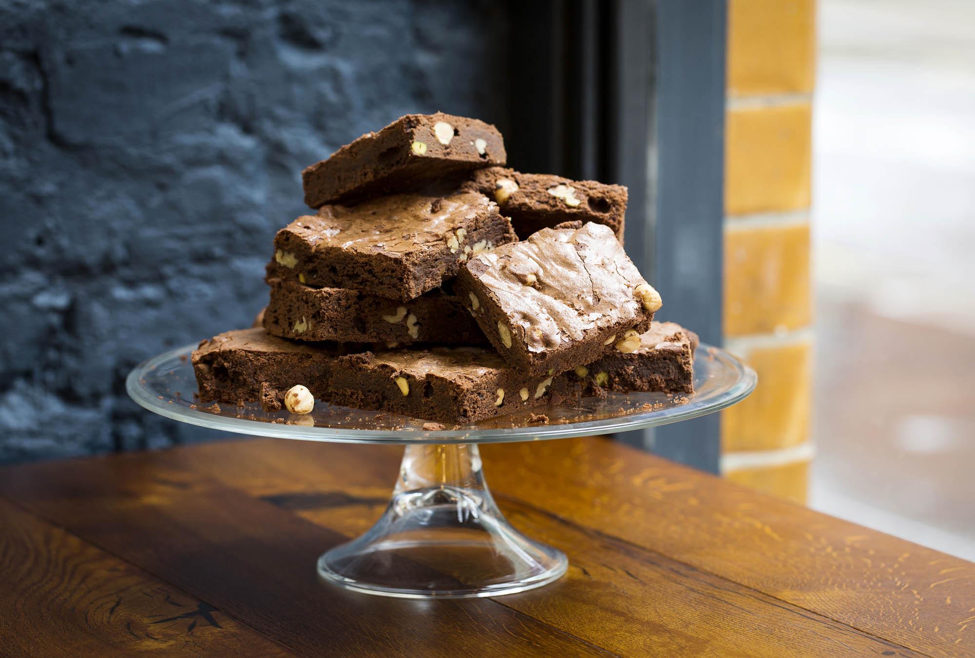 A stack of chocolate brownies on a glass cake stand