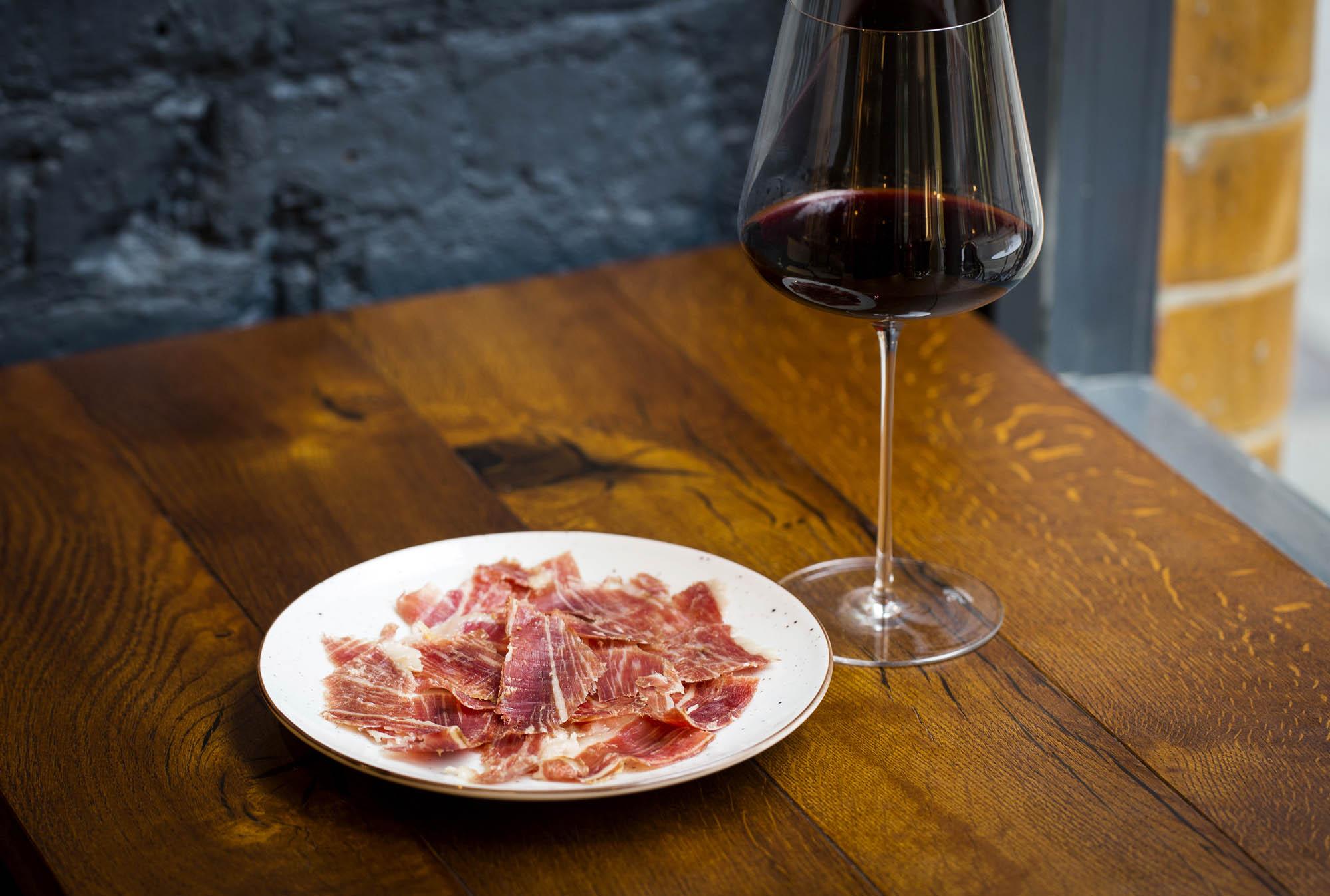 Sliced Iberico ham beside a glass of red wine