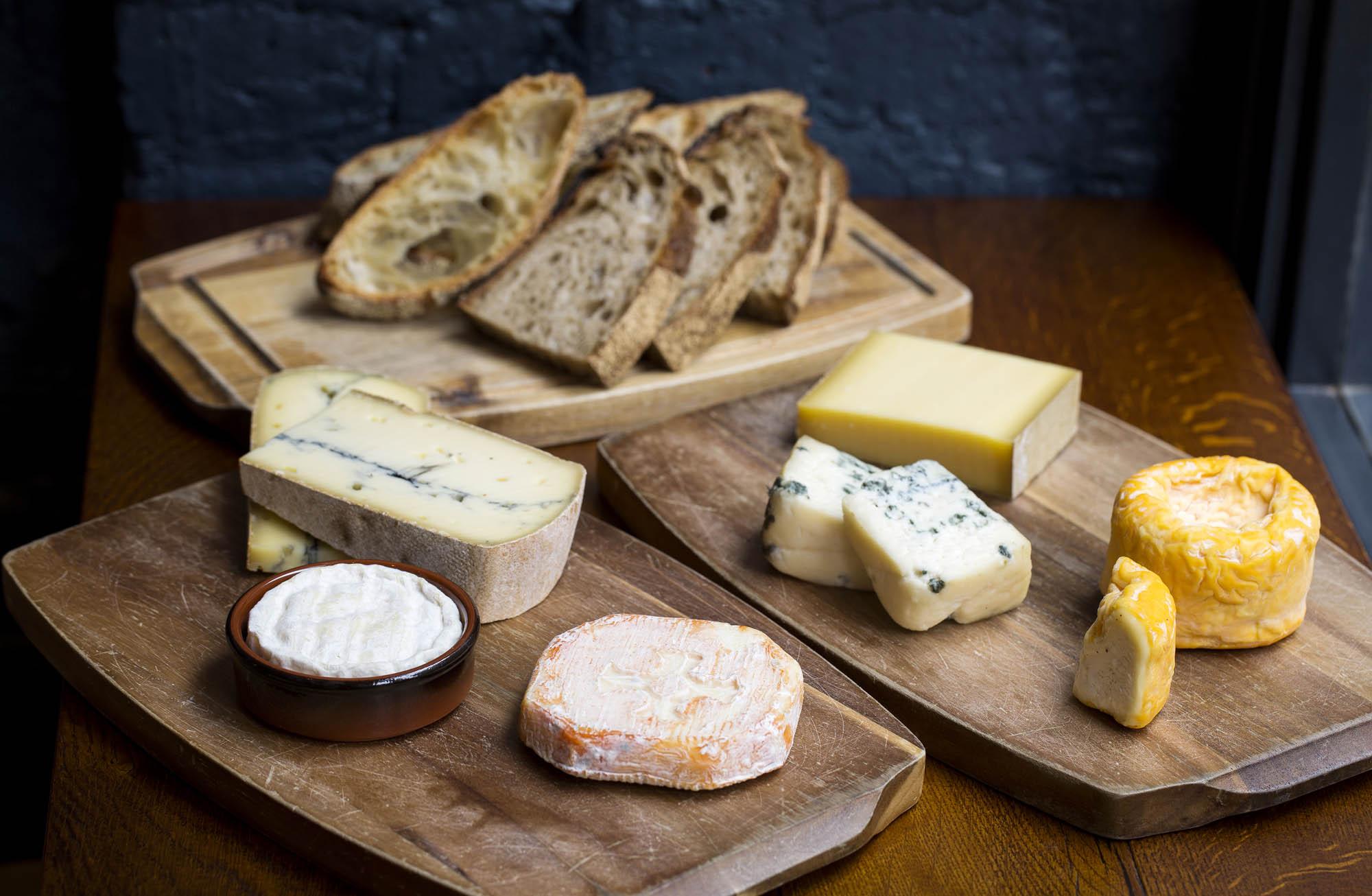 Boards of cheese and sliced sourdough on a dark wooden table