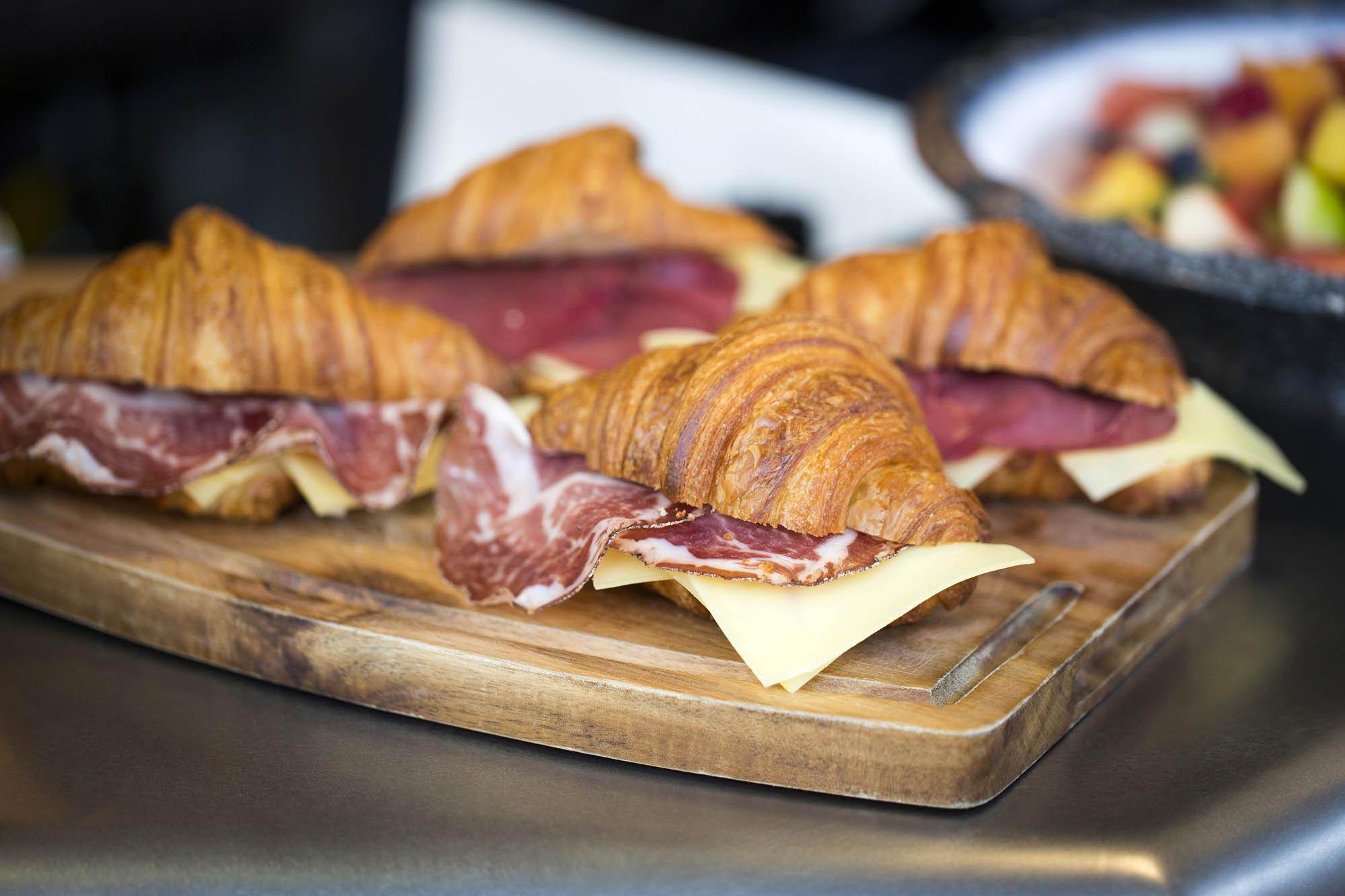 Croissants filled with cured ham and cheese on a wooden board